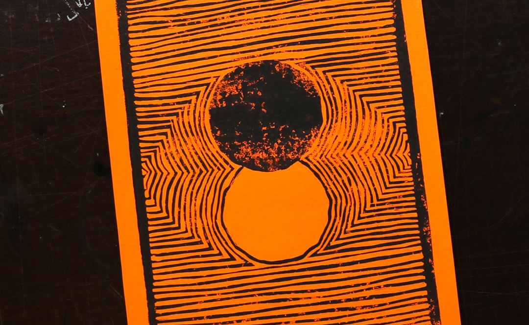 Cadrage rapproché d'une linogravure réalisée sur un papier orange fluo à l'encre noie. L'illustration est posée sur une table noire