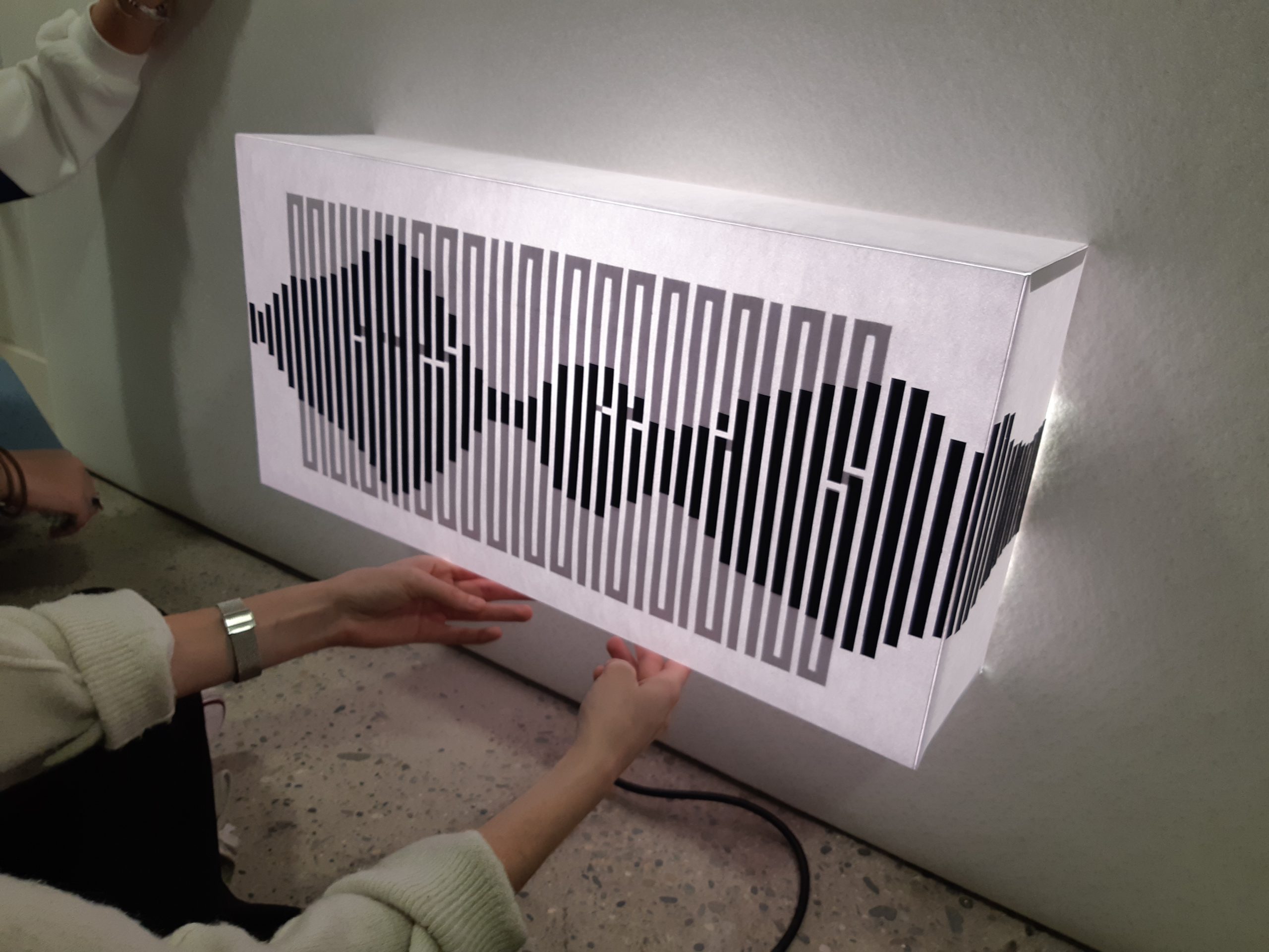 Photographie montrant 2 filles installant le lustre sur la porte servant d'installation finale pour le projet de workshop Only The Sound Remains